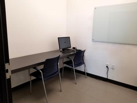 View of study room with desk top computer, desk and whiteboard