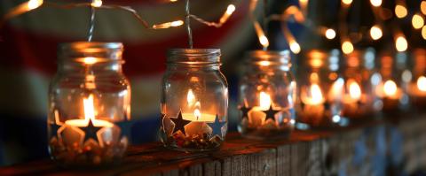 A row of mason jars with vinyl cut outs and tealights