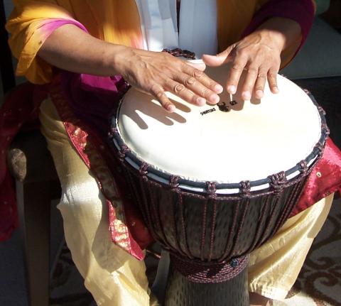 A photo of a person playing a Djembe drum.