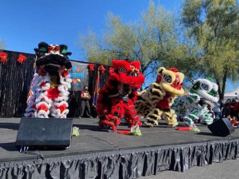 A photo of performers in lion costume dancing on a stage.