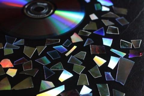 Image of pieces of a CD over a black background. 