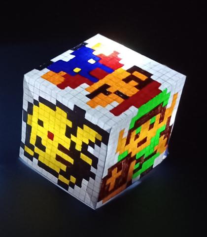 Paper folded into a cube with video game characters, and an LED inside.