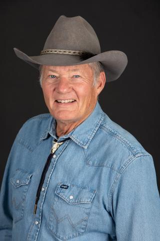 Headshot of Dan McCorison wearing a cowboy hat, jean shirt and bolo tie