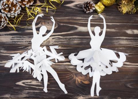 White paper craft ballerinas over a wooden background.