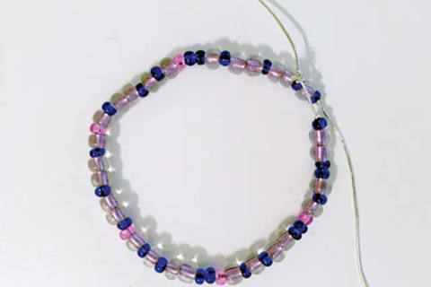 bracelet made out of blue, white, and purple glass beads threaded on elastic string