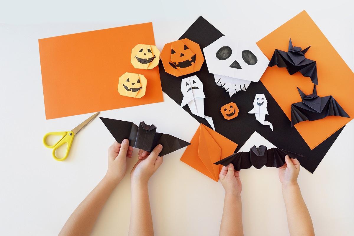 Image of hands folding black and orange paper. 