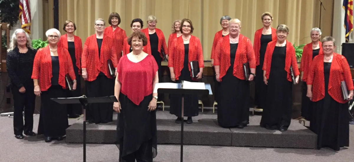 A photo of women in black dresses with red shawls and a piano