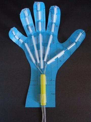 Blue hand cut out with straws and string on a black background.  