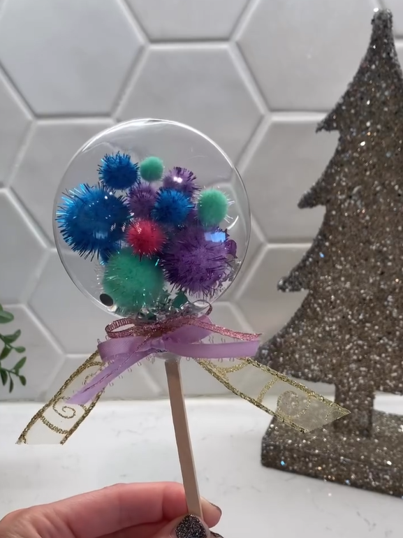 Clear ornament full of colorful pompoms. 